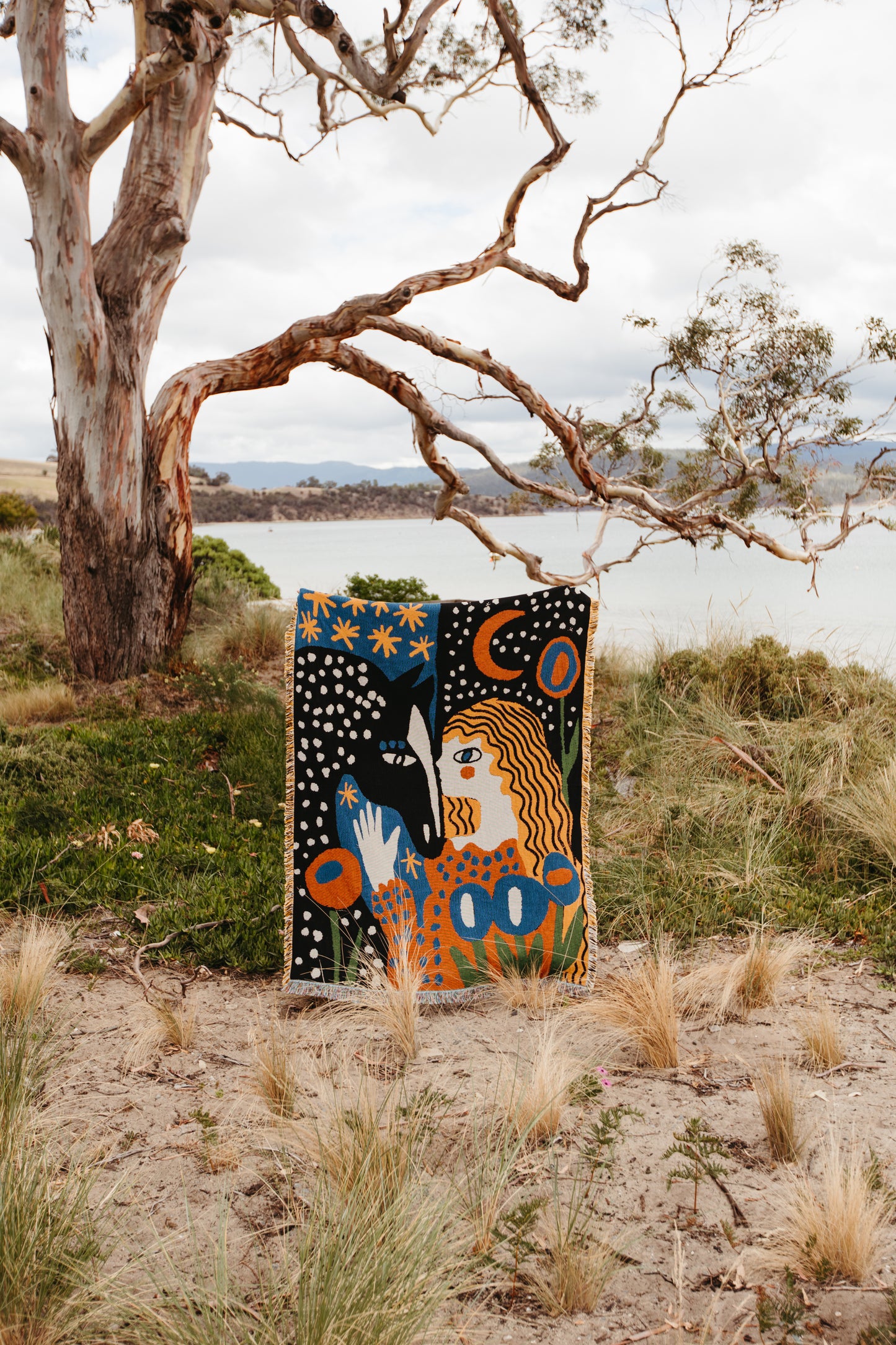 Alma woven blanket by Enikő Katalin Eged for slowdownstudio displayed outdoors against natural landscape, blending art textile with environment