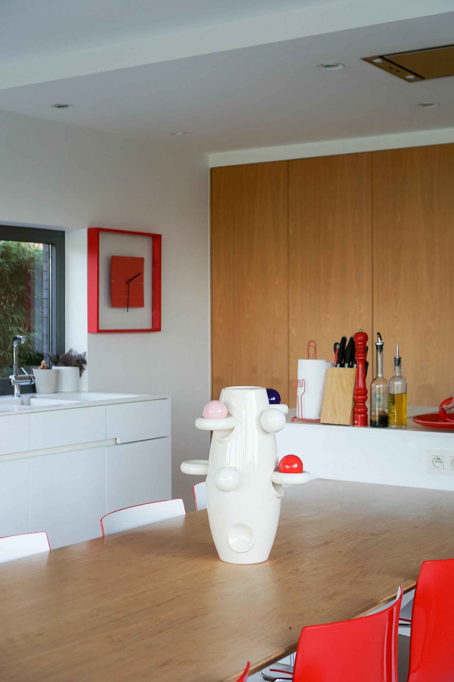 Rocket vase sculpture by Malwina Konopacka — ceramic piece adorned with colorful ball motifs, styled on a table in a contemporary kitchen with red accents.