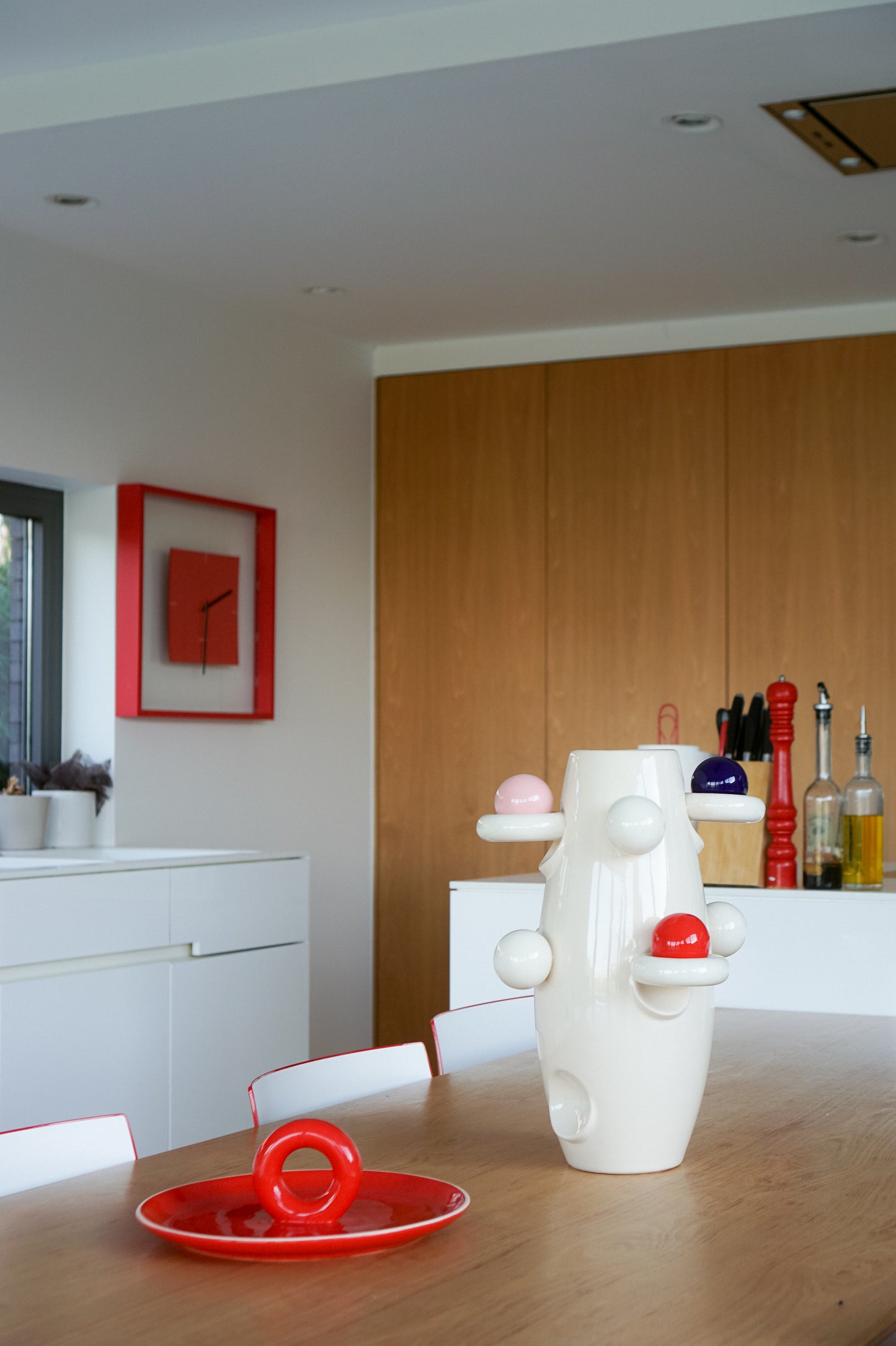 Aniela red platter by Malwina Konopacka, placed on a table in a modern kitchen featuring red accents.