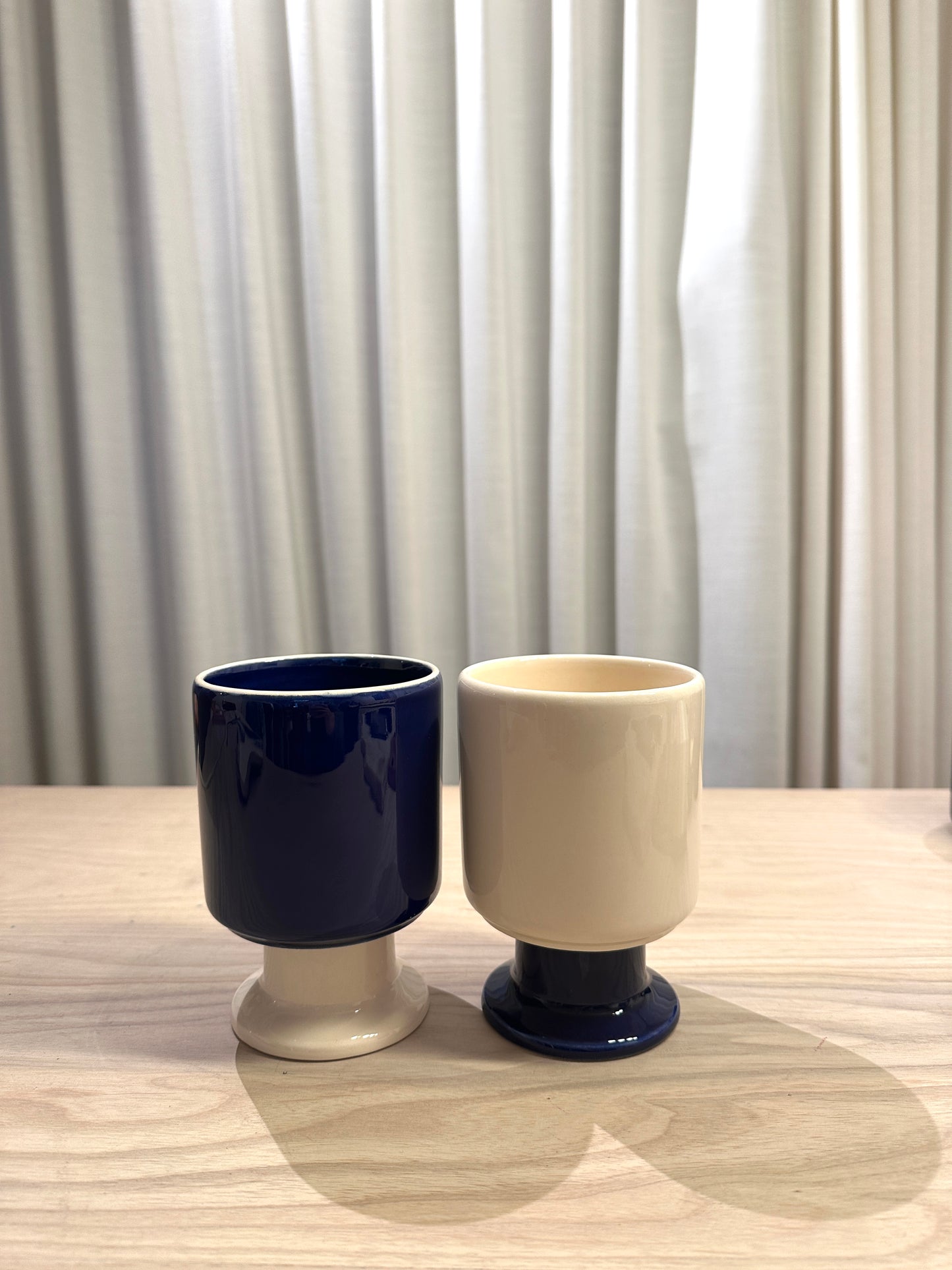 WIT ceramic mug by Malwina Konopacka in ecru and cobalt, a playful sculptural cup with a goblet-like stem, part of the curated RUIMTE collection.