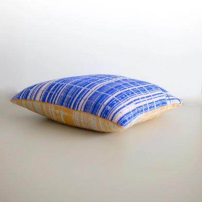 Handwoven decorative pillow by Emma Terweduwe in blue and yellow textile pattern on a neutral background