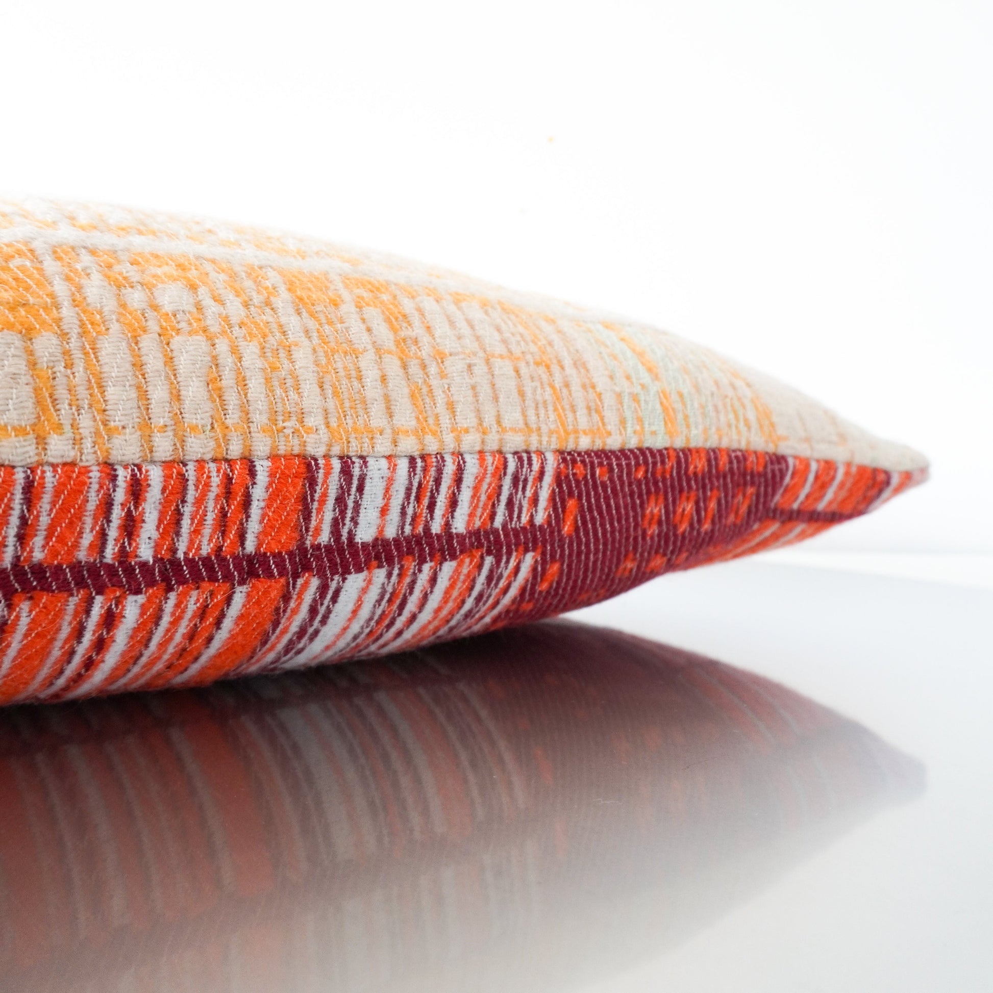 Detail of jacquard-woven pillow by Emma Terweduwe in peach and orange tones