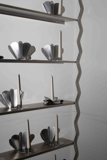 Close-up of WAVE stainless steel shelves styled with design objects, brushed steel finish by The Good Living & Co.