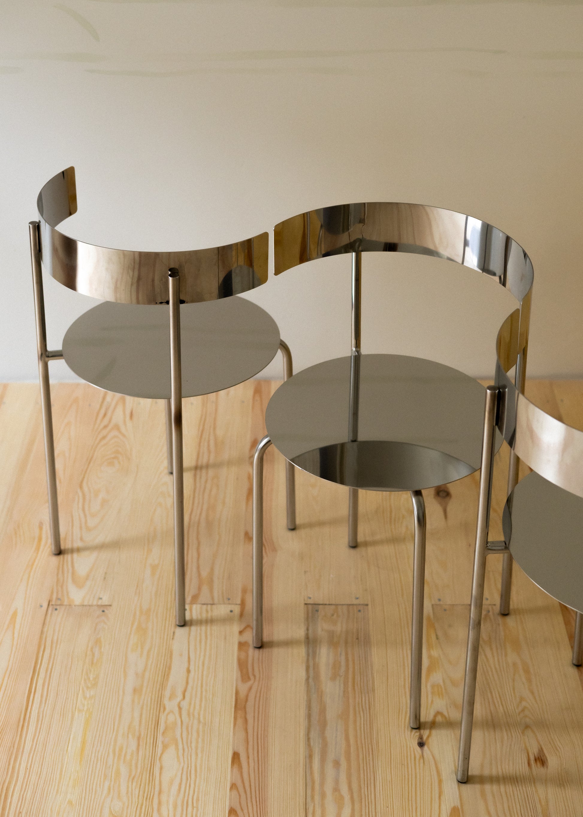 Two MEADOW polished steel chairs styled in a warm interior setting with wooden flooring, The Good Living & Co.