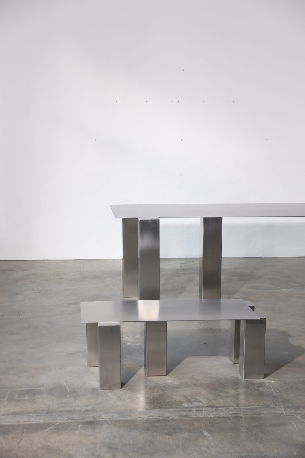 TRIUM coffee table in brushed stainless steel with structured rectangular legs, studio view, by The Good Living & Co