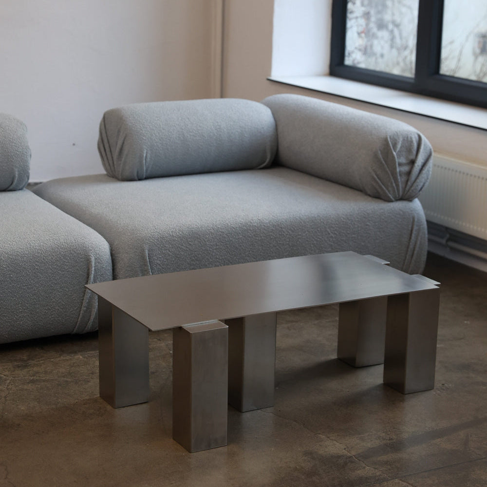 ATRIUM coffee table in brushed steel with bold rectangular legs, styled in a living room with grey modular sofa, by The Good Living & Co.