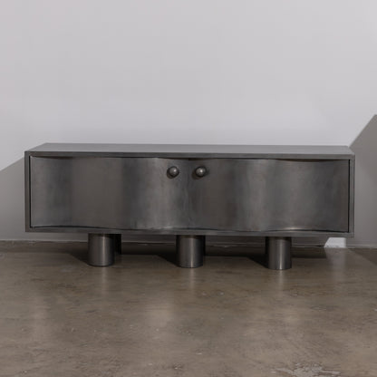 MOTION commode in brushed  steel with curved front doors, round knobs and cylindrical legs, by The Good Living & Co.