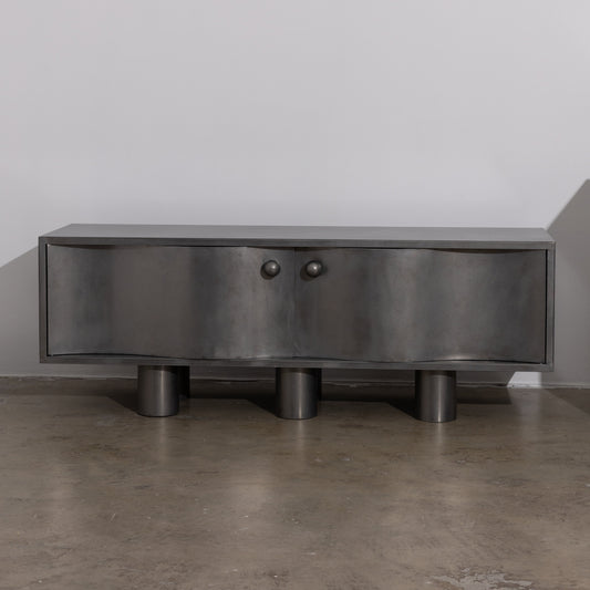 MOTION commode in brushed  steel with curved front doors, round knobs and cylindrical legs, by The Good Living & Co.