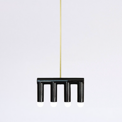 Handmade contemporary hanging lamp by Pani Jurek — black ceramic structure with brass details, featuring sculptural geometric forms suspended from a single point.