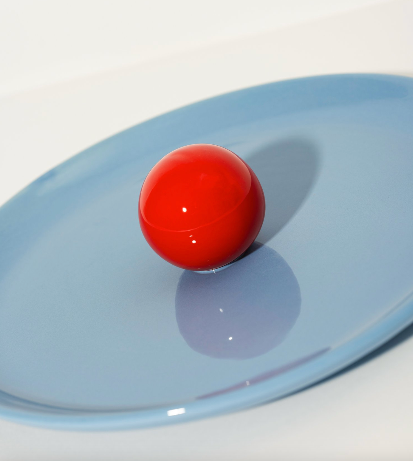 Blue ceramic fruit platter by Malwina Konopacka with a ball-shaped handle, styled on a white background.