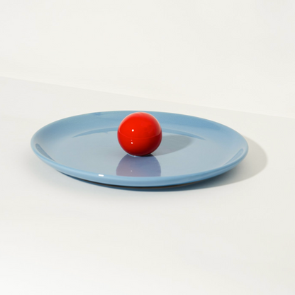 Blue ceramic fruit platter by Malwina Konopacka with a ball-shaped handle, styled on a white background.