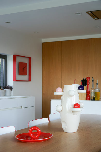 Aniela red platter by Malwina Konopacka, placed on a table in a modern kitchen featuring red accents.
