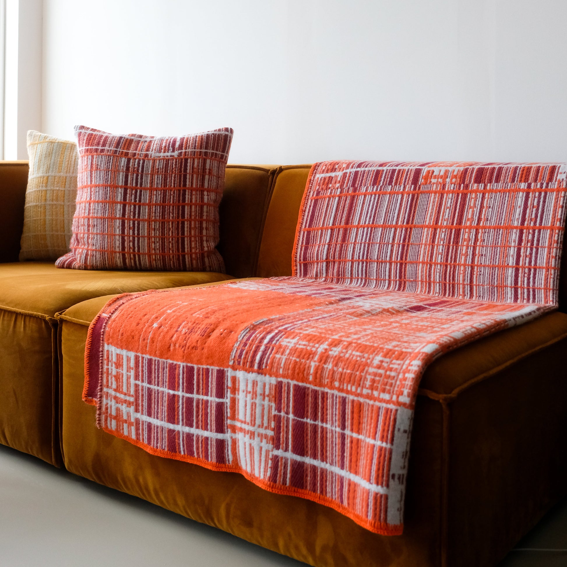 Jacquard-woven pillow by Emma Terweduwe styled on a sofa with matching throw blanket