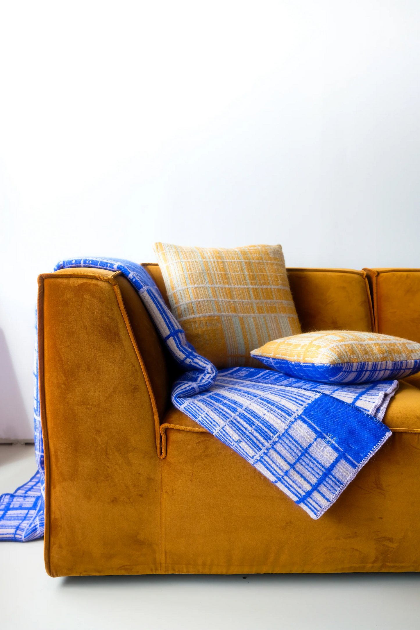 Emma Terweduwe handwoven pillow styled on a mustard yellow sofa in a contemporary interior