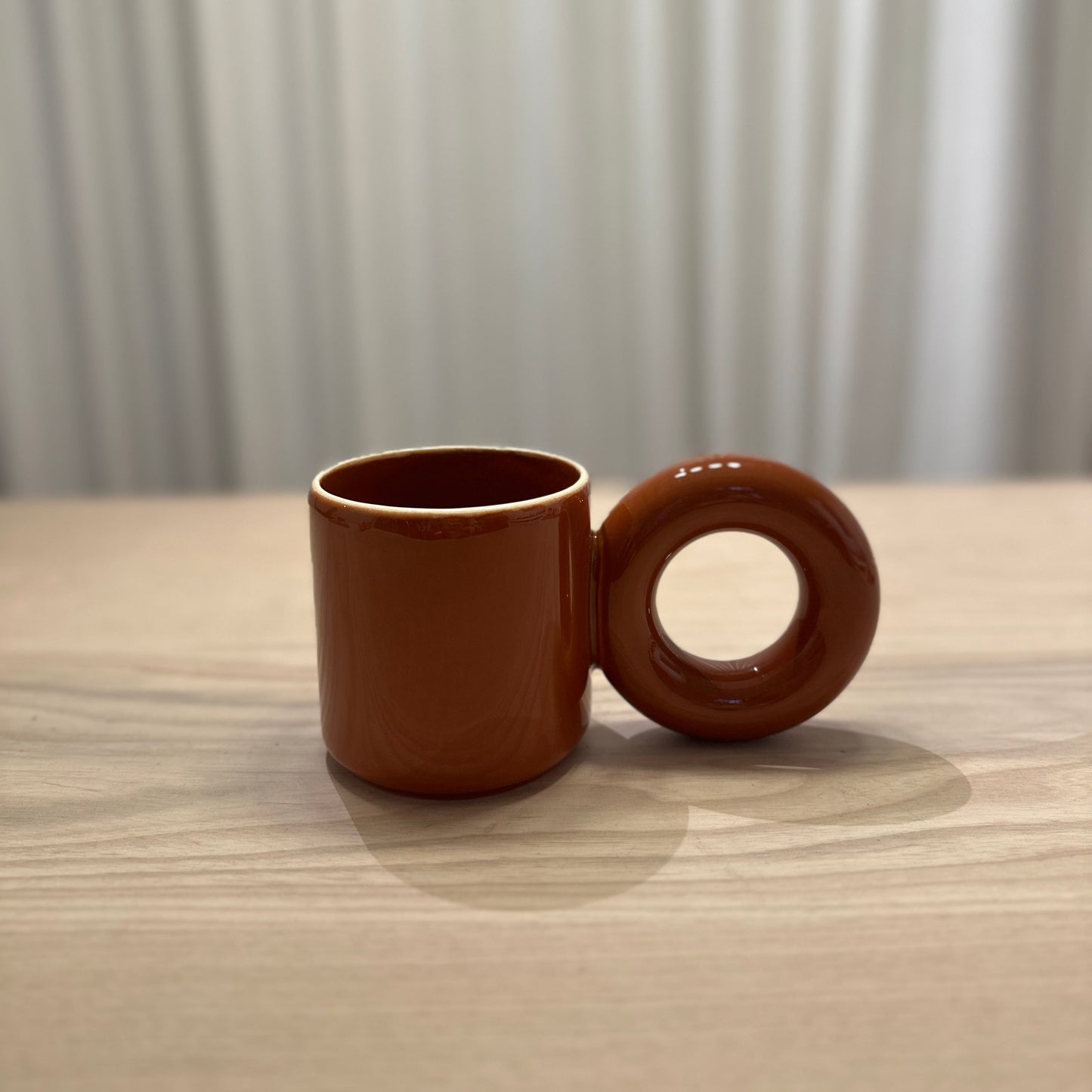 Brown mug by Malwina Konopacka featuring the sculptural round handle and handcrafted ceramic finish from the RUIMTE curated collection.