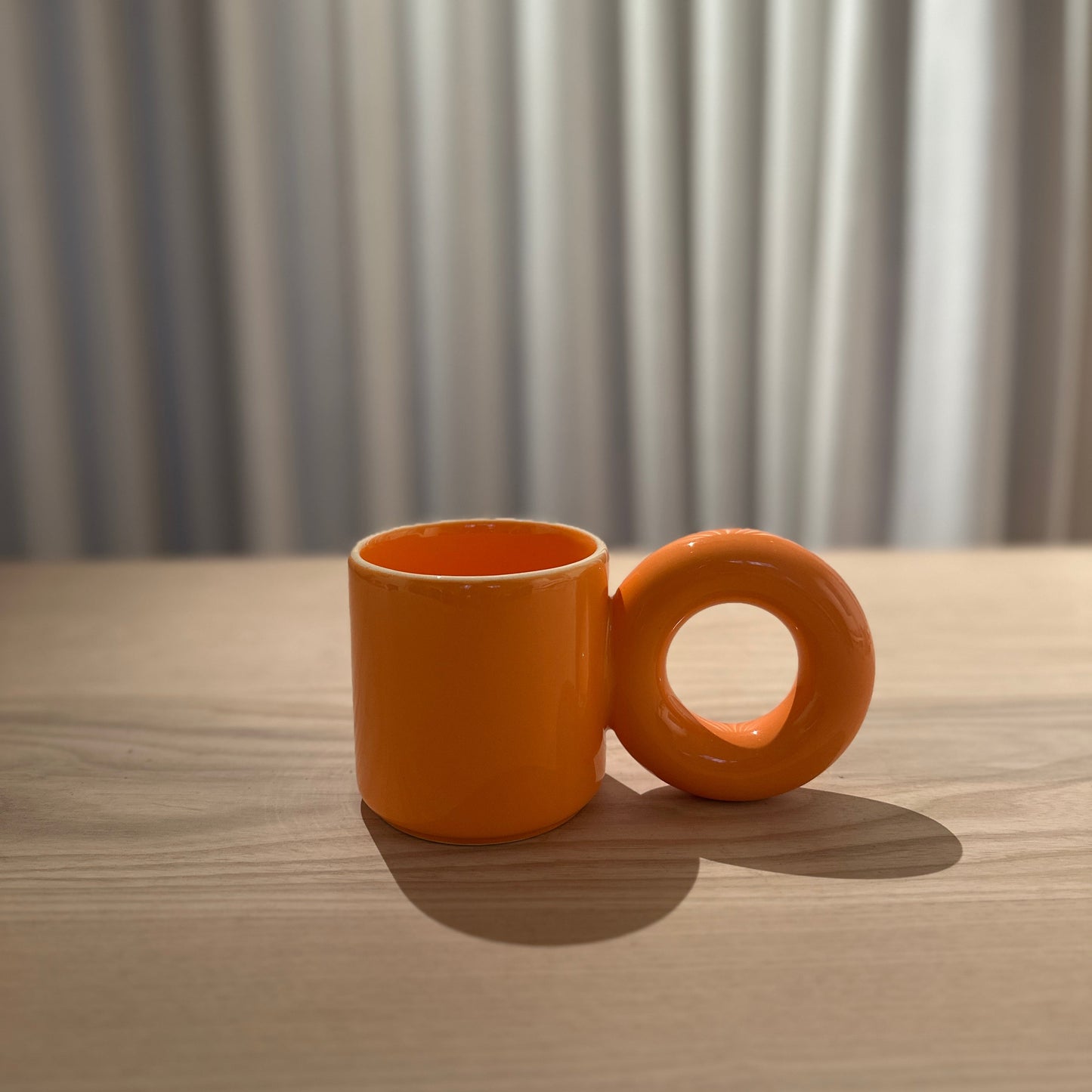 Oranje mok van Malwina Konopacka met de sculpturale ronde oor-greep en handgemaakte keramische afwerking uit de gecureerde RUIMTE collectie.