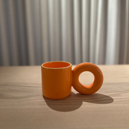 Oranje mok van Malwina Konopacka met de sculpturale ronde oor-greep en handgemaakte keramische afwerking uit de gecureerde RUIMTE collectie.