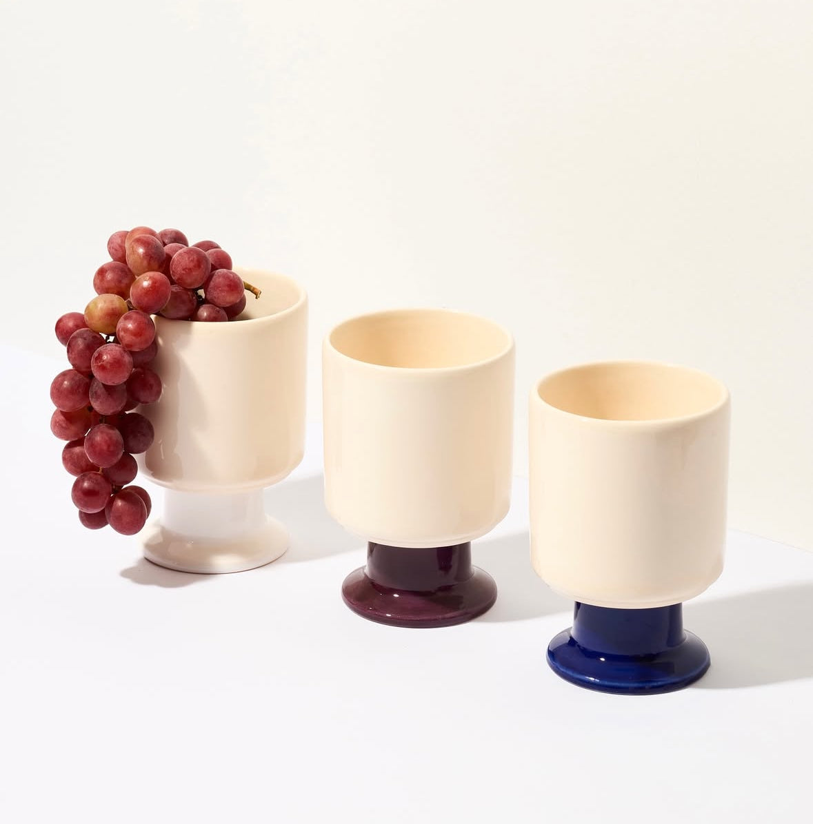 WIT ceramic mug by Malwina Konopacka in ecru and cobalt, a playful sculptural cup with a goblet-like stem, part of the curated RUIMTE collection