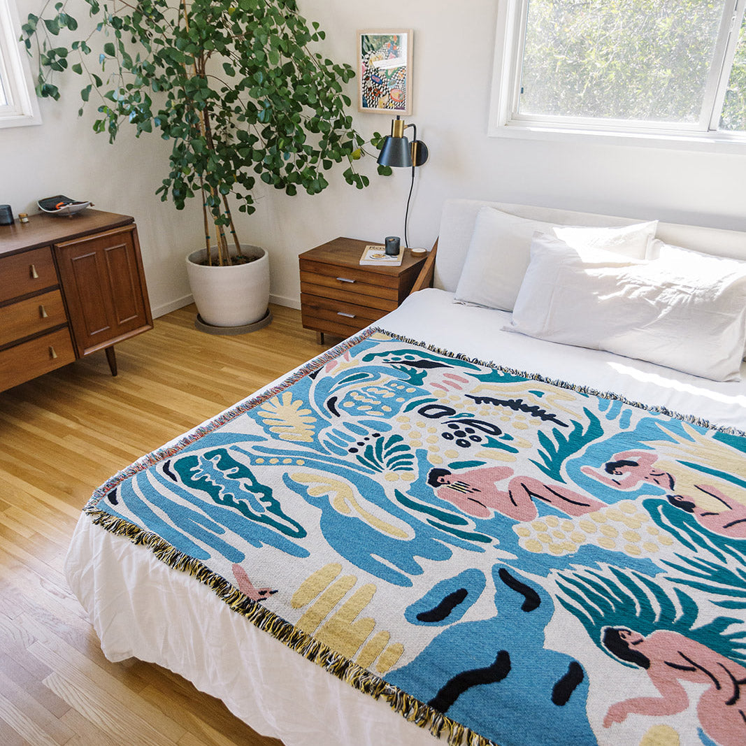 Kimbie woven throw blanket by Maitaimai styled on a bed as a functional art textile