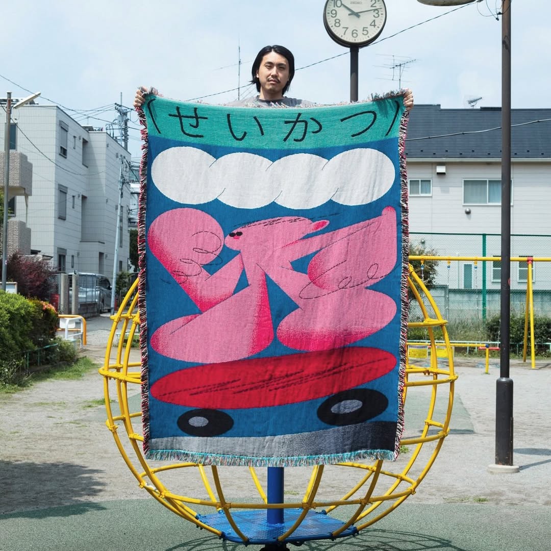 Suzukki woven throw blanket by Shun Sasaki hanging as textile wall art in an outdoor urban setting