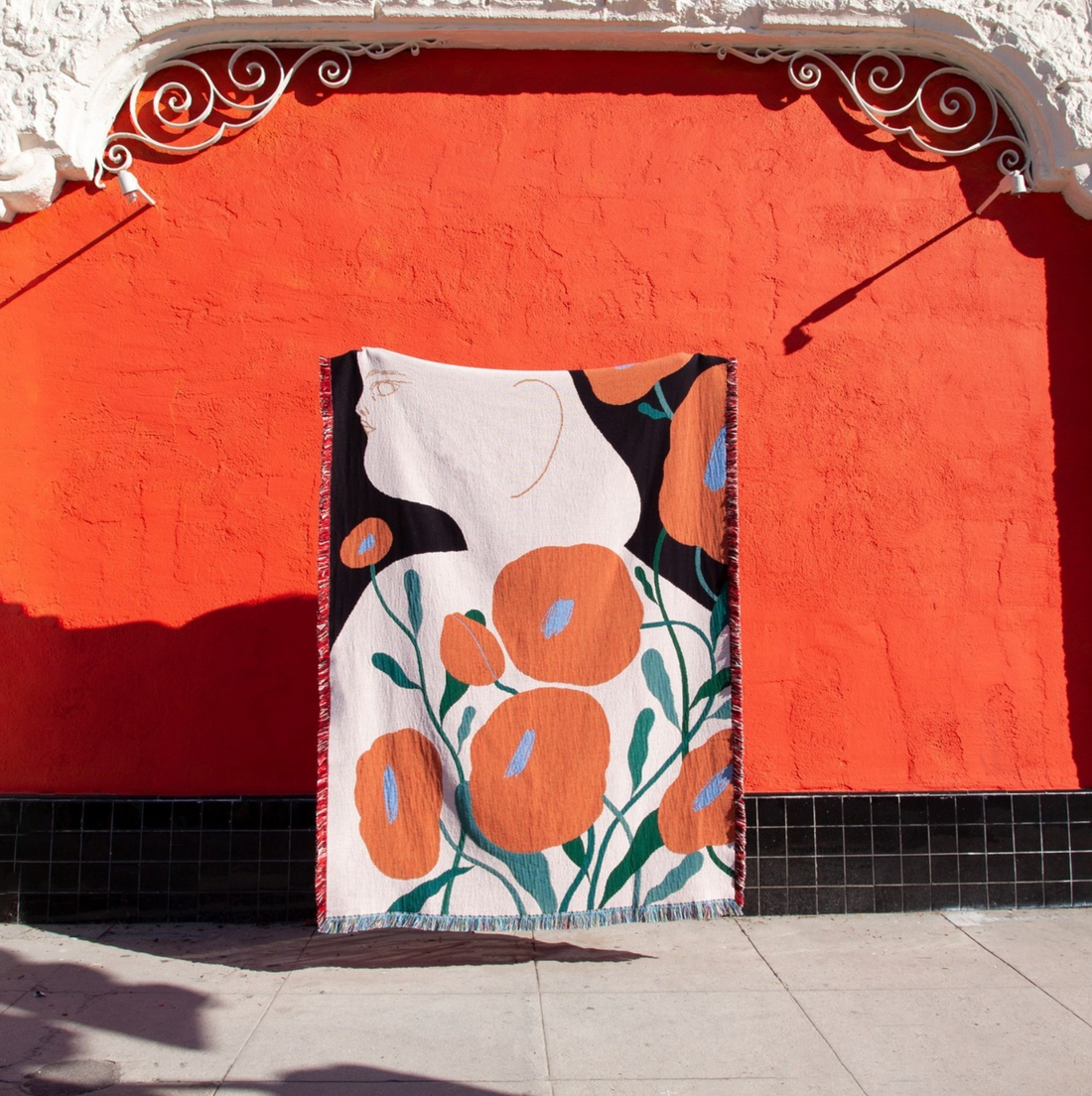 Melba woven throw blanket by Suvi Suitiala hanging as textile wall art in an outdoor setting